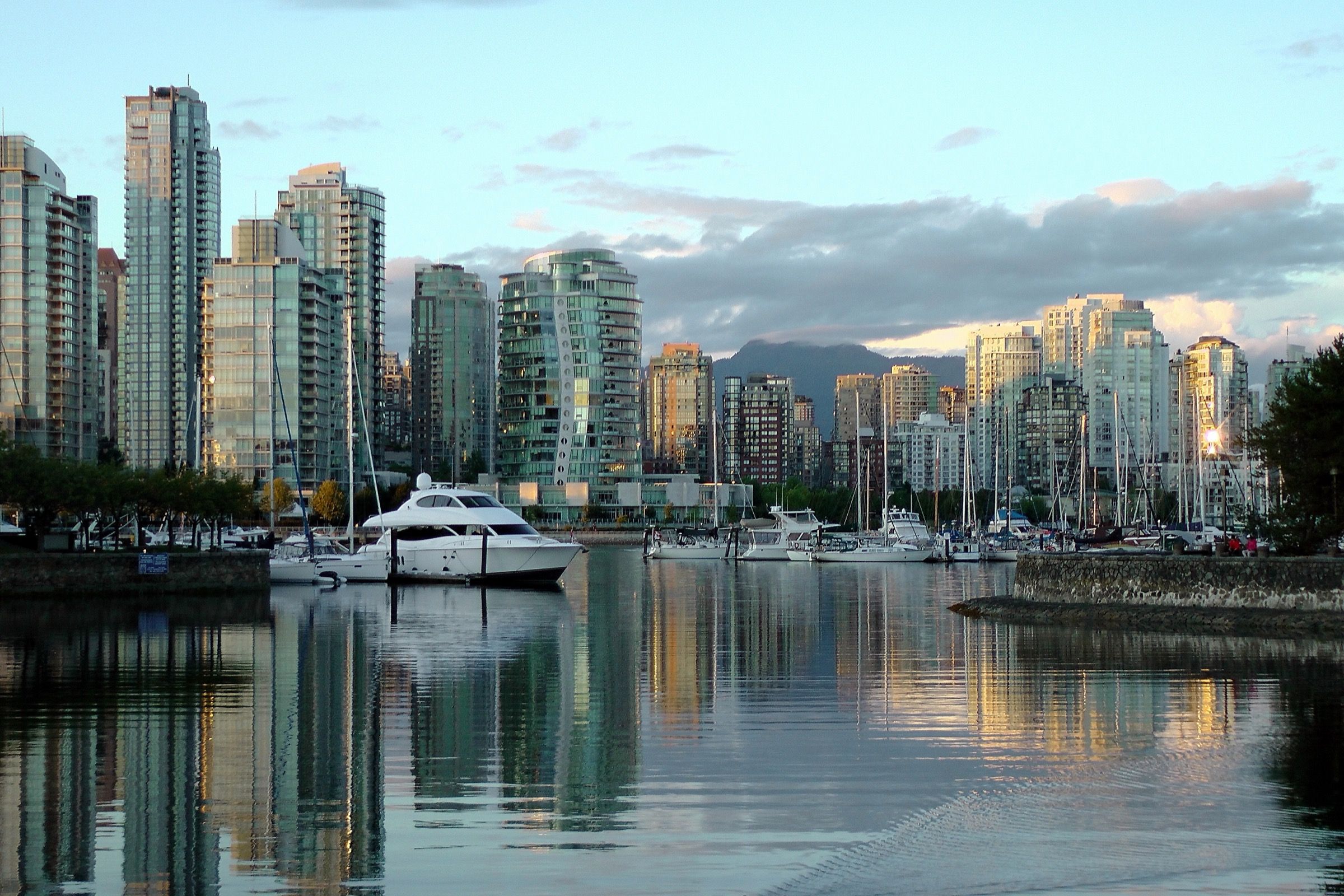 Yachts moored in False Creek at dusk against the Vancouver skyline and North Shore mountains