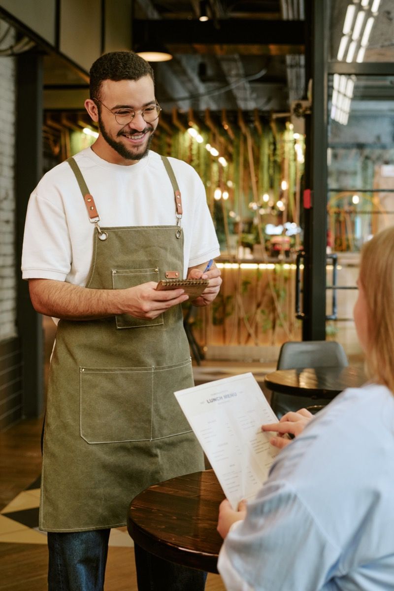 Friendly waiter taking order at restaurant